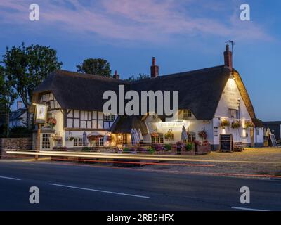 Il pittoresco edificio pubblico con tetto di paglia, il Leone Rosso, si trova sulla strada che attraversa lo storico henge di Avebury nel Wiltshire. Foto Stock