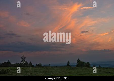 Nuvola di Cirro, arancione dall'ultima luce del sole che tramonta, sopra un paesaggio collinare nei Vosgi Foto Stock