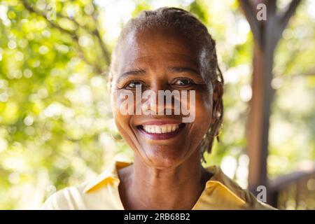 Ritratto di una donna afroamericana anziana felice nella natura soleggiata. Stile di vita senior, relax, pensione e benessere in natura, inalterato. Foto Stock