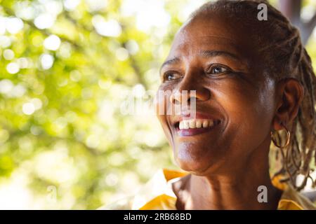Ritratto di una donna afroamericana anziana felice nella natura soleggiata. Stile di vita senior, relax, pensione e benessere in natura, inalterato. Foto Stock