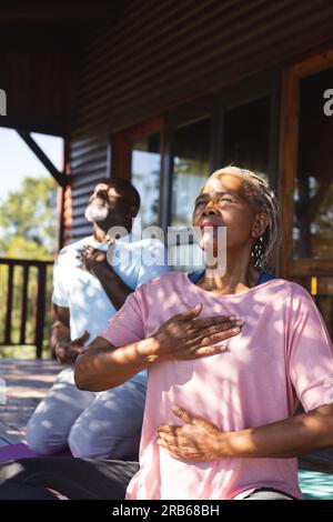 Coppie afroamericane anziane che praticano meditazione yoga sulla terrazza soleggiata. Stile di vita senior, relax, benessere nella natura, fitness, esercizio fisico Foto Stock
