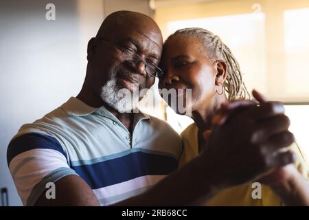 Felice coppia afro-americana che abbraccia e balla a casa. Stile di vita senior, relax e pensionamento, inalterato. Foto Stock