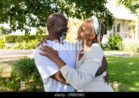 Felice coppia afro-americana anziana sorridente l'una all'altra e abbracciata in un giardino soleggiato. Stile di vita senior, felicità, vita domestica e pensione, u Foto Stock