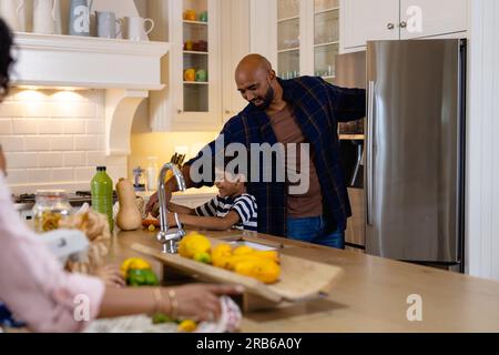 I genitori e i figli birazziali sono felici e hanno fatto acquisti di generi alimentari in cucina e rifornito di frigorifero. Cibo, shopping, stile di vita sano, ecologia, famiglia e cupole Foto Stock