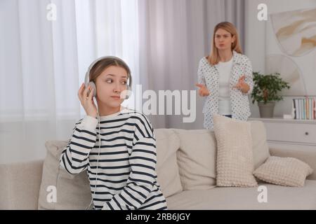 Figlia adolescente con le cuffie che ignora sua madre a casa Foto Stock