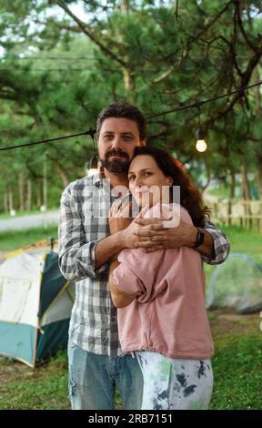 Le giovani coppie sposate si sentono felici e sorridono, in piedi nella foresta la sera Foto Stock