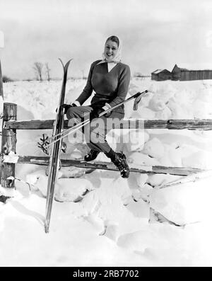 Collingwood, Ontario, Canada c. 1954 Una giovane sciatrice si prende una pausa al sole seduto su una staccionata. Foto Stock