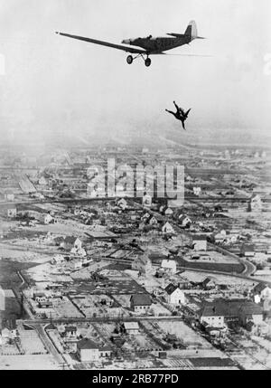 Germania: 24 maggio 1931 Willi Ruge si sta sforzando di prendere i primi autoritratti di Sky diving mentre salta da un aereo con un paracadute. Qui si tuffa prima dall'aereo per dare al suo collega Herr Boettcher l'effetto migliore per la sua fotografia. Foto Stock