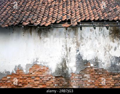 Una vecchia casa, con piastrelle rotte, demage e pareti in mattoni d'epoca per lo sfondo della carta da parati Foto Stock