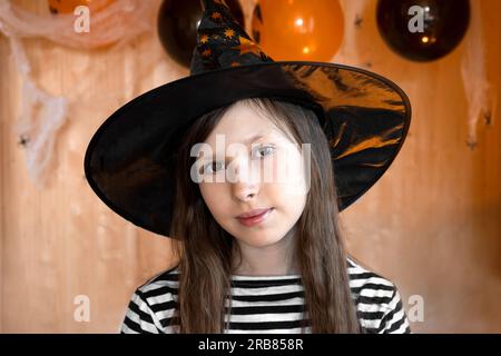 Halloween per bambini - una ragazza in un cappello da strega e un costume  da carnevale con palloncini arancioni e neri a casa. Pronto a festeggiare  Halloween Foto stock - Alamy