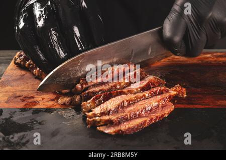 Succosa bistecca appena grigliata. lo chef taglia la carne fritta a fette Foto Stock