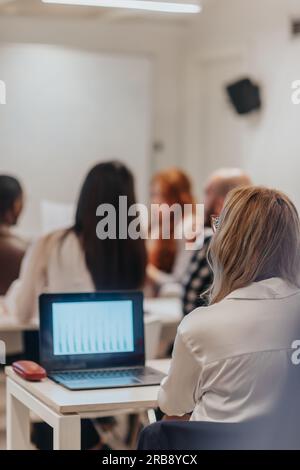 Immagine retrospettiva del team aziendale multirazziale che discute, pianifica nuove idee e strategie aziendali durante il brainstorming in aula Foto Stock