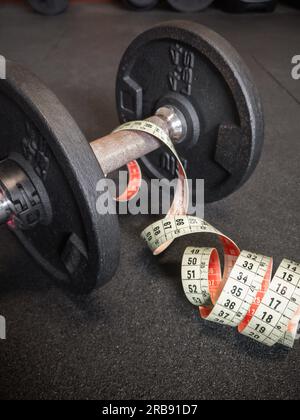 Primo piano di manubri e metro neri arrugginiti da 4,4 kg o 2 kg sul pavimento della palestra. Fitness, allenamento con pesi o stile di vita sano Foto Stock