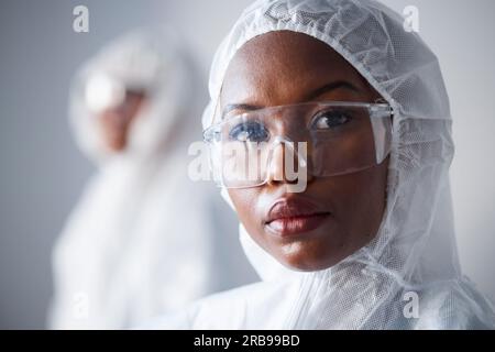 Scienza, serietà e ritratto di una donna di colore in un laboratorio con una tuta per la sicurezza dal virus. Viso, ospedale e uno scienziato africano con occhiali e. Foto Stock