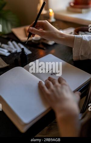 Lavoro creativo, passione, hobby. Tavolo da artista con candele brucianti che disegnano inchiostro nel notebook. Foto Stock