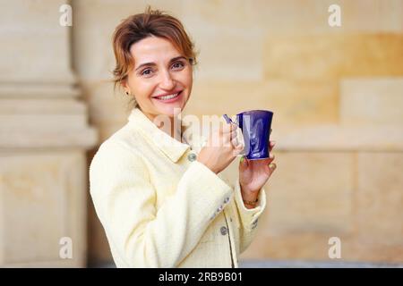 La donna felice beve acqua termale minerale salutare in uno dei famosi centri medici e terapeutici europei di Karlovy Vary Foto Stock