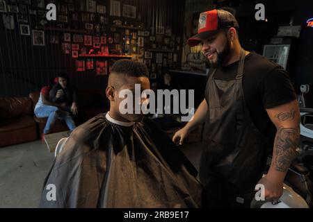 Parrucchiere al servizio del cliente in salone. Giovane uomo che si fa tagliare i capelli alla moda al barbiere.Francoforte sul meno, Germania Foto Stock