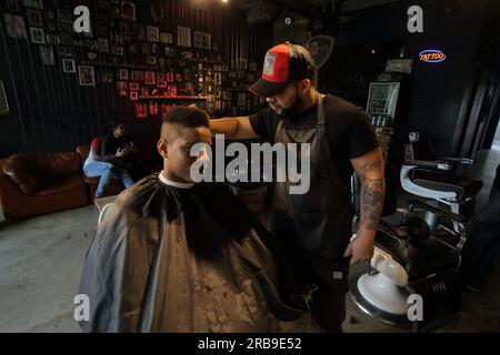 Parrucchiere al servizio del cliente in salone. Giovane uomo che si fa tagliare i capelli alla moda al barbiere.Francoforte sul meno, Germania Foto Stock