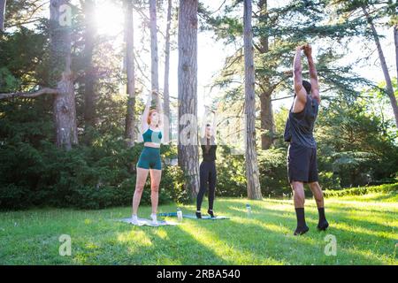 Un allenatore di fitness con i suoi studenti durante una lezione all'aperto, concetto di vita sana Foto Stock