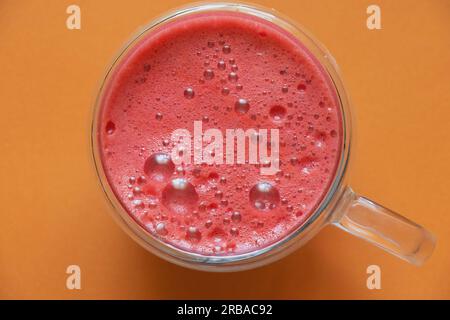 spremuta di succo rosso appena spremuto in una tazza per colazione con schiuma su fondo isolato Foto Stock