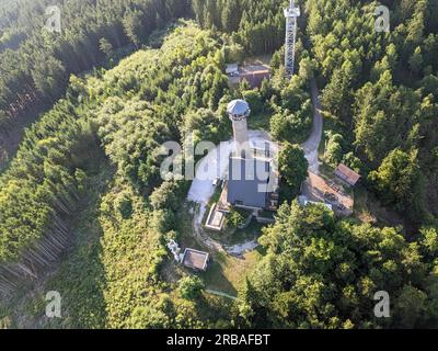 Vista aerea della cima della collina di Svatobor con una storica torre panoramica con una capanna turistica, una torre di telecomunicazioni e una torre di conversione TV Foto Stock