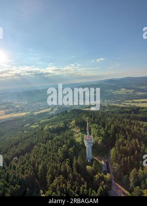 Vista aerea della cima della collina di Svatobor con una storica torre panoramica con una capanna turistica, una torre di telecomunicazioni e una torre di conversione TV Foto Stock