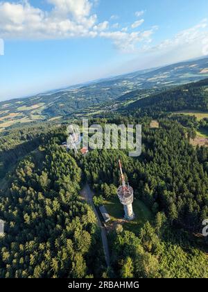 Vista aerea della cima della collina di Svatobor con una storica torre panoramica con una capanna turistica, una torre di telecomunicazioni e una torre di conversione TV Foto Stock