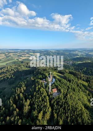 Vista aerea della cima della collina di Svatobor con una storica torre panoramica con una capanna turistica, una torre di telecomunicazioni e una torre di conversione TV Foto Stock