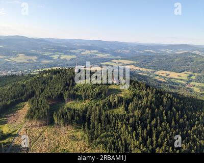 Vista aerea della cima della collina di Svatobor con una storica torre panoramica con una capanna turistica, una torre di telecomunicazioni e una torre di conversione TV Foto Stock