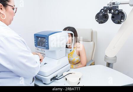 Specialista che esegue un esame oculistico su una paziente di sesso femminile. Optometrista che controlla la vista di un paziente con un autorefrattore Foto Stock