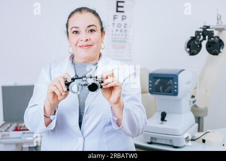 Ritratto dell'optometrista che tiene in mano la lente di messbrille in laboratorio. Optometrista specialista che regge il telaio di prova optometrico Foto Stock