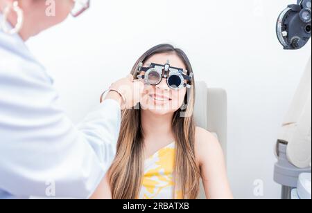 Paziente sorridente con telaio di prova optometrista. Primo piano dell'optometrista che esamina il paziente con il telaio di prova optometrista Foto Stock