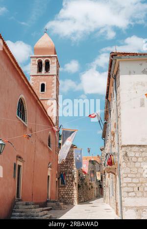 Campanile della Chiesa di S.. Justine e la stretta strada della città vecchia di Rab sull'isola di Rab, Croazia. Foto Stock