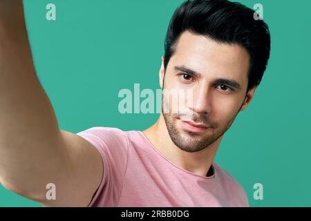 Primo piano ritratto di bell'uomo che prende selfie su blu sfondo Foto Stock