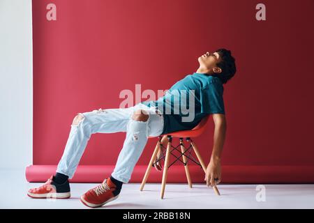 Ritratto di giovane stanco seduto su sedia in studio. Concetto di emozioni Foto Stock