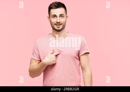 Stupito giovane uomo che guarda sorpreso indicando se stesso, assicurandosi che sentì rish su sfondo rosa. Concetto di emozioni Foto Stock