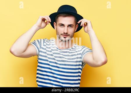 Ritratto di moda di giovane hipster uomo in cappello su sfondo giallo Foto Stock