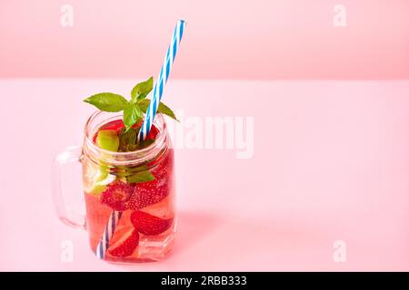 Fragola limonata fatta in casa in un vasetto di muratore con spazio di copia su sfondo rosa. Cocktail rinfrescante freddo, festa, concetto estivo Foto Stock