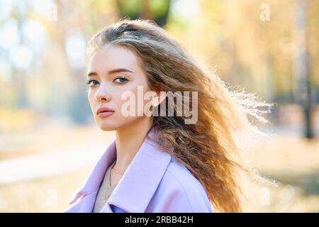 Ritratto di elegante bella donna in posa all'aperto in autunno parco godendo giorno di sole. Concetto di stagione autunnale, bellezza femminile Foto Stock