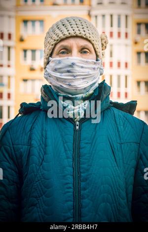 Una povera donna anziana indossa una maschera casalinga per proteggersi da virus come il coronavirus, noto anche come covid-19, o SARS e MERS. È in un Foto Stock