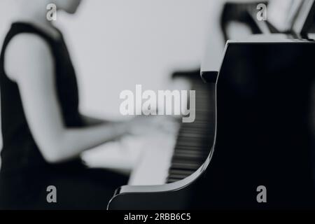 Una ragazza elegante siede al grande concerto e suona il pianoforte Foto Stock