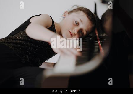 Una ragazza elegante siede al grande concerto e suona il pianoforte Foto Stock