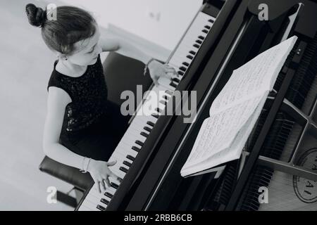 Una ragazza elegante siede al grande concerto e suona il pianoforte Foto Stock