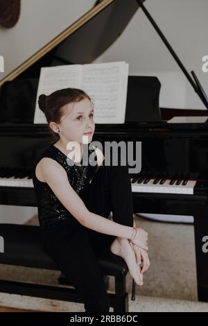 Una ragazza elegante siede al grande concerto e suona il pianoforte Foto Stock