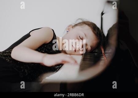 Una ragazza elegante siede al grande concerto e suona il pianoforte Foto Stock