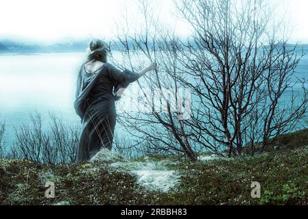 Una donna celtica catturata si affaccia sulla mistica nebbia del fiordo. Desidera lasciare questa terra dei vichinghi e tornare nella sua patria e nei suoi parenti. Foto Stock