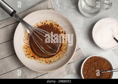 Montare la panna per il caffè dalgona e gli ingredienti su un tavolo grigio chiaro, a base piatta Foto Stock