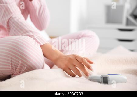 Giovane donna malata che misura la temperatura a letto, primo piano Foto Stock