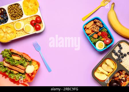 Cestini per il pranzo con diversi piatti gustosi su sfondo lilla Foto Stock