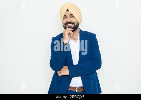 Felice giovane uomo d'affari indiano sikh con vestito blu in piedi in posa isolato su sfondo bianco. Concetto aziendale. shot di lunghezza ll Foto Stock
